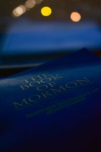Blurred image of the Book of Mormon cover with background bokeh lights, creating a serene ambiance.